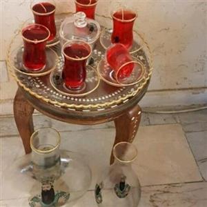 سرویس16پارچه استکان کمرباریک نعلبکی سینی تُنگ و گلدان بلورین شاه عباسی.  استکان هاحاوی شمع  ژله ای قرمز  رنگ. برند پیروز